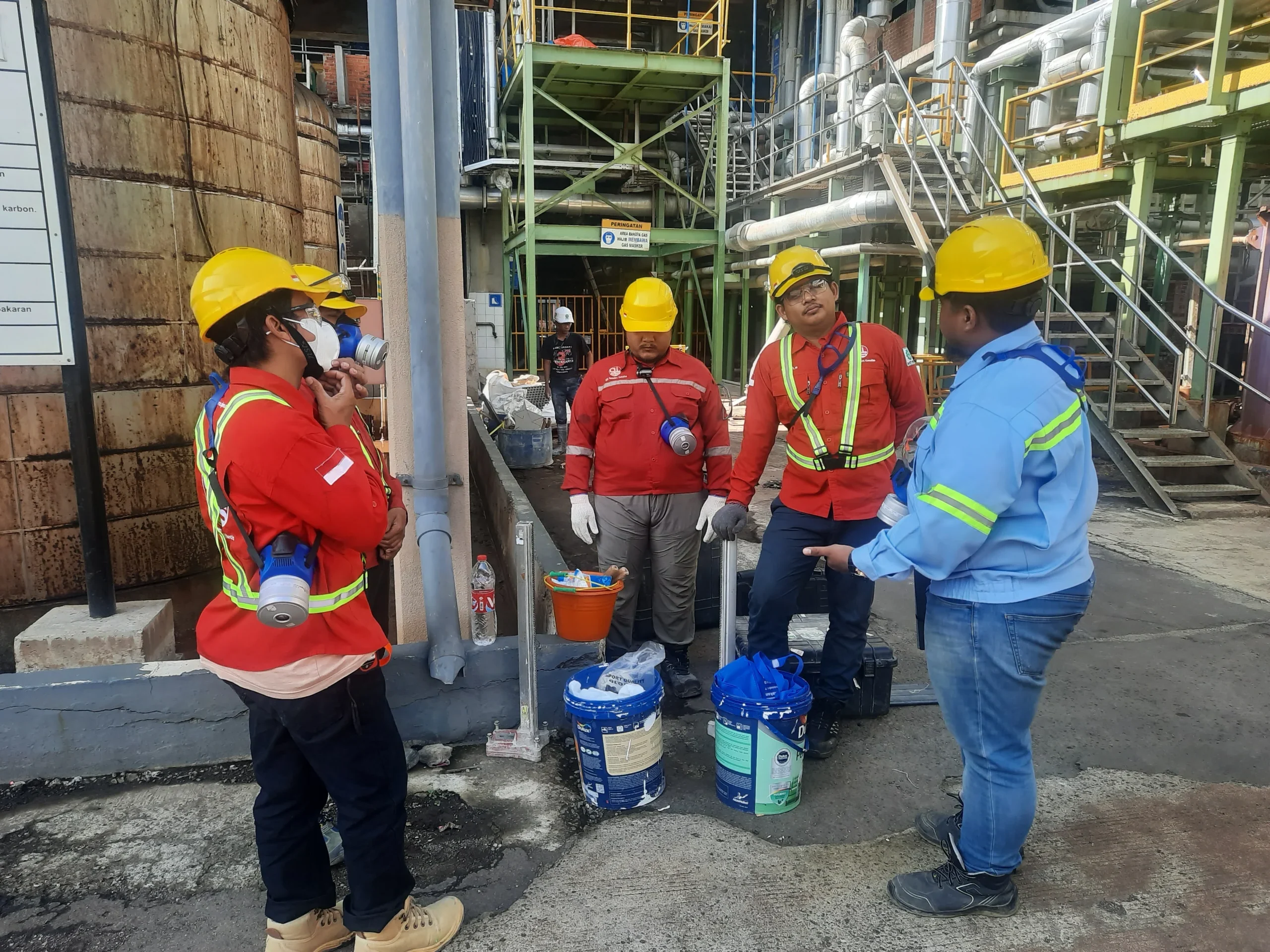 Koordinasi tim berperlengkapan keselamatan di area instalasi industri